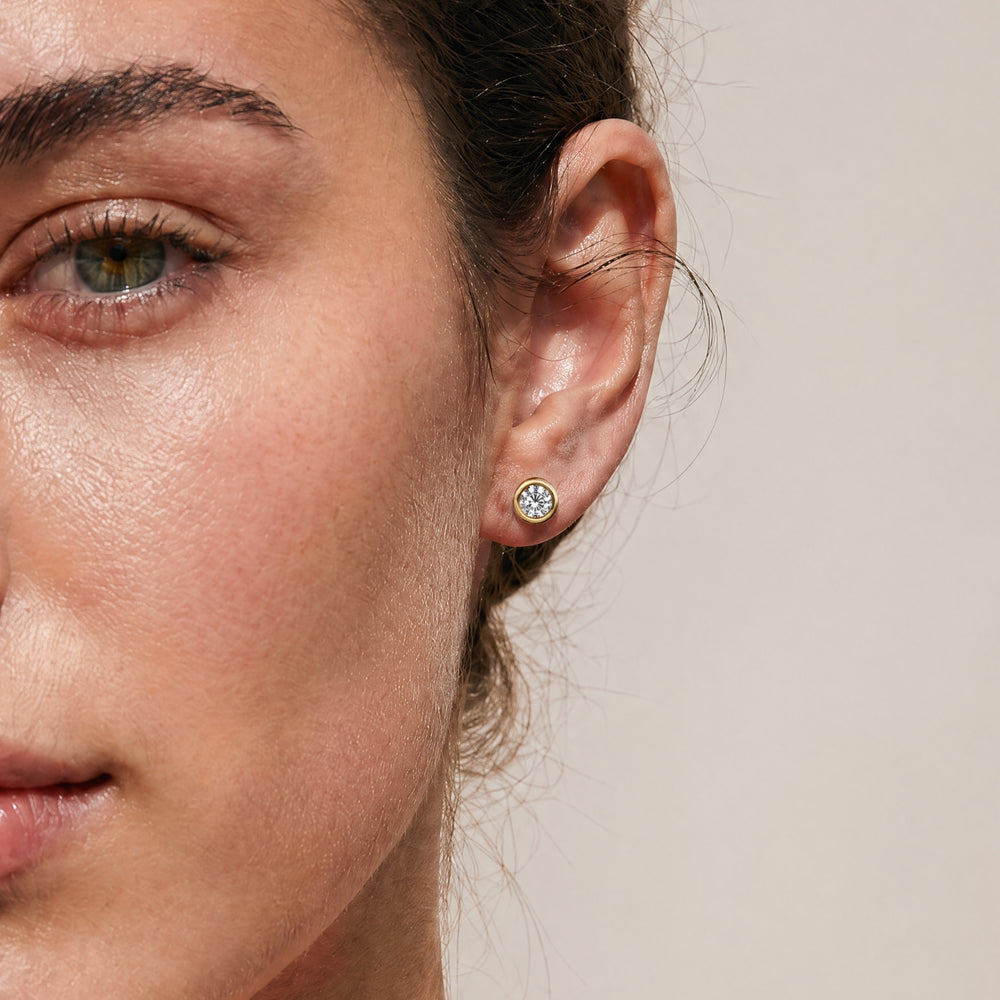 Close-up of ALBA earrings in yellow gold with smooth bezel setting